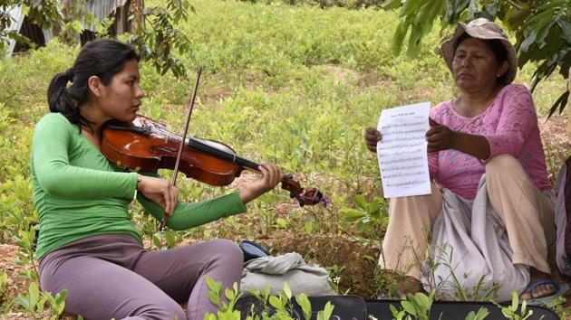 Chura grew up picking coca leaves on her parents’ land. When she received visitors on a suffocatingly hot and humid day, she took out her instrument and filled the family home with music, as her mother Lidia turned the pages of sheet music. “I feel calm (playing the viola). It’s like you forget everything -- you’re focused on playing, you forget your problems,” Chura said. (Aizar Raldes / AFP) 