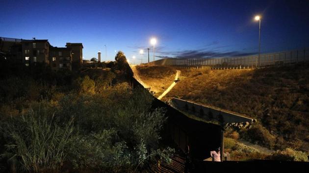 A Central American migrant lowers herself down from atop the border wall onto the US side. A large number have decided to make new lives in Mexico, applying for work permits and taking jobs at local factories while they wait as the US government processes about 100 asylum requests a day at the San Ysidro crossing, the United States’ busiest. (Rebecca Blackwell / AP) A Central American migrant lowers herself down from atop the border wall onto the US side. A large number have decided to make new lives in Mexico, applying for work permits and taking jobs at local factories while they wait as the US government processes about 100 asylum requests a day at the San Ysidro crossing, the United States’ busiest. (Rebecca Blackwell / AP)