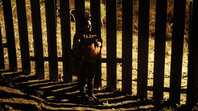 A woman holding a baby peers through the US border fence as she tries to reach a point where scores of migrants have been crossing in recent days, now blocked by private security. Thousands of migrants are living in crowded tent cities in Tijuana after undertaking a grueling journey from Central America to the US border. (Rebecca Blackwell / AP) A woman holding a baby peers through the US border fence as she tries to reach a point where scores of migrants have been crossing in recent days, now blocked by private security. Thousands of migrants are living in crowded tent cities in Tijuana after undertaking a grueling journey from Central America to the US border. (Rebecca Blackwell / AP)