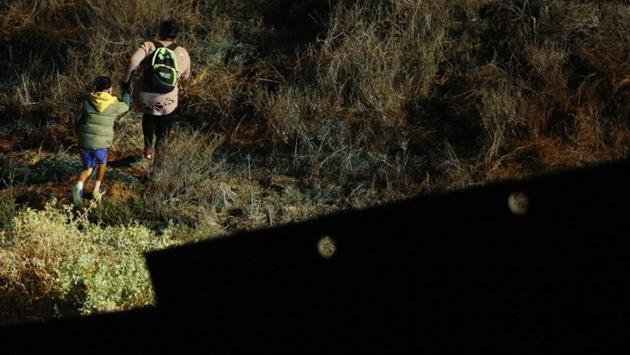 A woman and child migrant start up a hill in San Ysidro, California after climbing over the US border wall. In twos or threes — occasionally by the dozen — they arrive at the border wall and manage to get over. Often within minutes, border officers quickly arrive to escort them to detention centers and begin “credible fear” interviews. (Rebecca Blackwell / AP) A woman and child migrant start up a hill in San Ysidro, California after climbing over the US border wall. In twos or threes — occasionally by the dozen — they arrive at the border wall and manage to get over. Often within minutes, border officers quickly arrive to escort them to detention centers and begin “credible fear” interviews. (Rebecca Blackwell / AP)