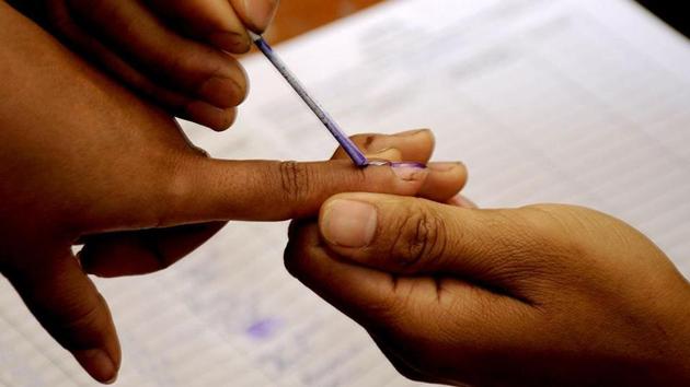 A polling official marks a voter with indelible ink prior to casting a ballot inside a polling station at Bungthuam in Mizoram. (AFP File photo)
