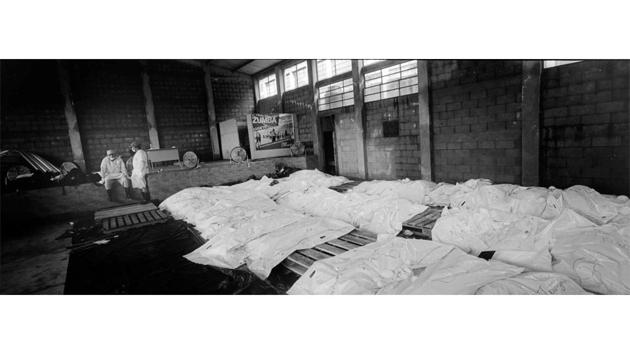 In a makeshift morgue, dozens of victims’ bodies wrapped in white bags formed a kind of silent corridor that ended with two exhausted forensic doctors taking a break after days and nights of continuous work. (Rodrigo Abd / AP) In a makeshift morgue, dozens of victims’ bodies wrapped in white bags formed a kind of silent corridor that ended with two exhausted forensic doctors taking a break after days and nights of continuous work. (Rodrigo Abd / AP)