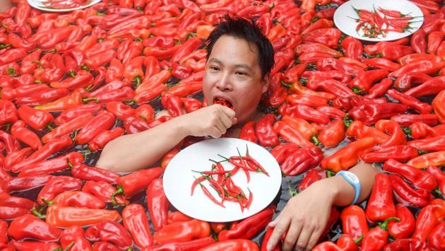 A competitor takes part in a chilli pepper eating contest in a hot spring filled with chilli peppers in the Mingyue Qiangu Scenic Area in Wentang Town, Jiangxi, China. The winner took one minute to eat 20 peppers. (Stringer / AFP) A competitor takes part in a chilli pepper eating contest in a hot spring filled with chilli peppers in the Mingyue Qiangu Scenic Area in Wentang Town, Jiangxi, China. The winner took one minute to eat 20 peppers. (Stringer / AFP)