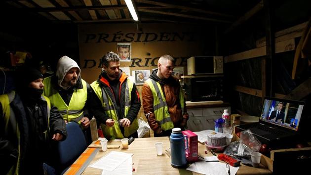 Protesters wearing yellow vests watch French President Emmanuel Macron on a TV screen in Bouguenais, France. Macron’s 13-minute address over the protests and economic disparity failed to quell the yellow vests. (Stephane Mahe / REUTERS) Protesters wearing yellow vests watch French President Emmanuel Macron on a TV screen in Bouguenais, France. Macron’s 13-minute address over the protests and economic disparity failed to quell the yellow vests. (Stephane Mahe / REUTERS)