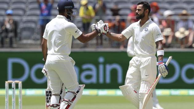 India's Virat Kohli, right, is congratulated by team mate Hanuma Vihari after Kohli scored a century during the second cricket test between Australia and India in Perth (AP)