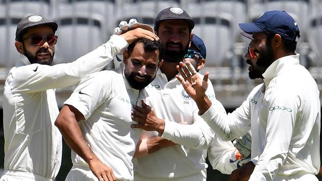 India's captain Virat Kohli (L) greets paceman Mohammed Shami (C) for his fifth wicket during day four of the second Test against Australia.(AFP)