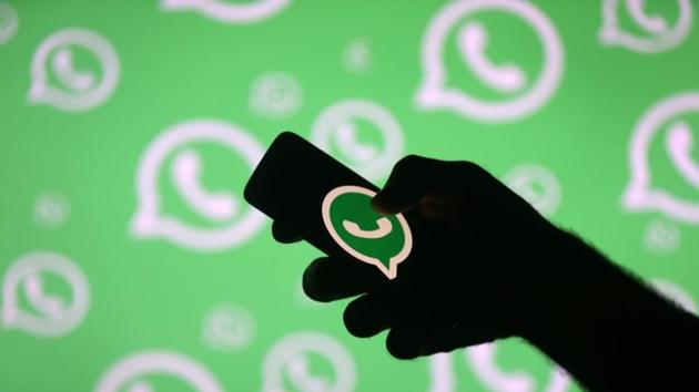 A man poses with a smartphone in front of displayed Whatsapp logo.(REUTERS)