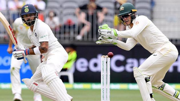 India's captain Virat Kohli plays a shot as Australia's captain and wicketkeeper Tim Paine looks on.(Reuters)