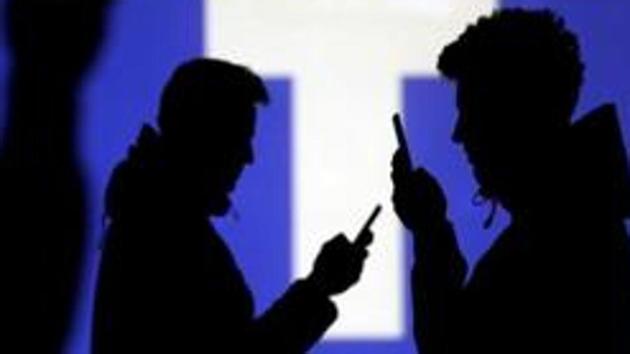 Silhouettes of mobile users are seen next to a screen projection of Facebook logo in this picture illustration taken March 28, 2018. REUTERS/Dado Ruvic/Illustration/Files(REUTERS)