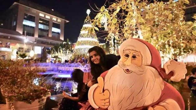 People take photographs infront of a Christmas tree at a mall in New Delhi.(Burhaan Kinu / Hindustan Times)