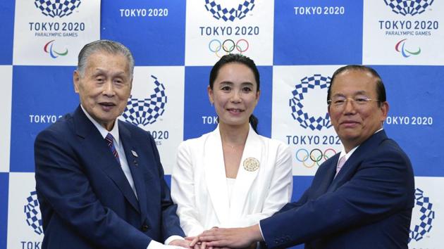 Japanese film director Naomi Kawase, center, Tokyo Olympic organizing committee President Yoshiro Mori, left, and Toshiro Muto, right, CEO of the Tokyo Organizing Committee of the Olympic and Paralympic Games, pose for photographers during a press conference. (AP)