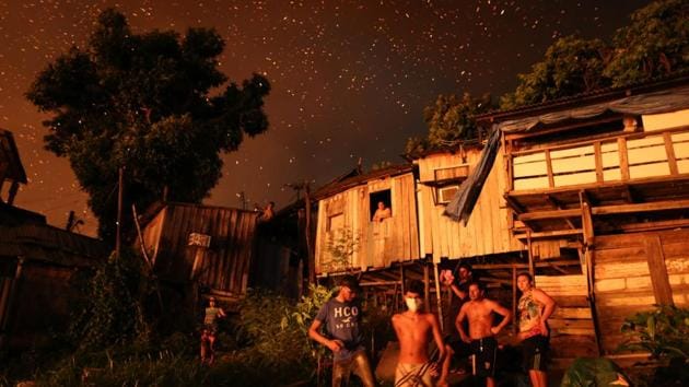 Residents of Educandos neighbourhood remain outside their houses, as firefighters try to control a massive fire, in Manaus, Amazonas state, Brazil. The fire destroyed at least 600 houses and its origin is still unknown. (Michael Dantas / AFP) 