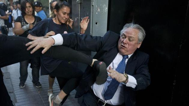 Ivan Arostica, president of Chile’s Constitutional Court, ties to avoid a kick by a protester as he leaves the court, which listened to arguments in favour and against conditional freedom for those convicted of human rights crimes, in Santiago, Chile. (Esteban Felix / AP) 