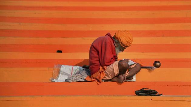 A sadhu reads a holy scripture on the steps of Maujgiri Ghat at bank of the river Yamuna, in Prayagraj, Uttar Pradesh. (PTI)