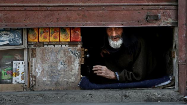 A shopkeeper peeps from inside a half closed shop during a shut down in Srinagar, Jammu and Kashmir. (Mukhtar Khan / AP)
