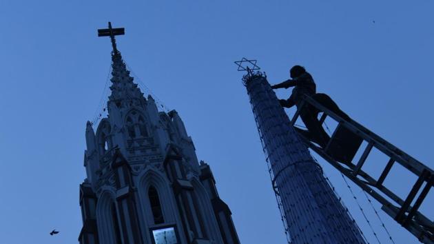 A worker arranges a star atop a Christmas tree in front of St Mary’s Basilica in Bengaluru, Karnataka, ahead of Christmas. (Manjunath Kiran / AFP)