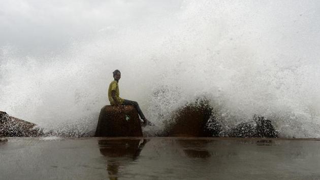A young boy sits on a concrete block as waves hit a breakwater at Kasimedu fishing harbour, as cyclone Phethai approaches the eastern Indian coast, in Chennai, Tamil Nadu. (Arun Sankar / AFP)