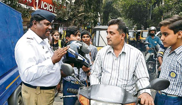 A police constable along with students of RCM Gujarati school create awareness about helmets near Phadke Haud chowk on Monday. Helmet sellers blame slowdown in police action for the staggering sales figures.(Ravindra Joshi/HT PHOTO)