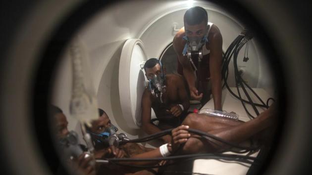 Miskito divers stricken with decompression sickness climb into a hyperbaric chamber. Decompression sickness is usually treatable with sessions in such high-pressure, oxygen-rich chambers, but there are only a few available along the coast, and divers must often wait several days before they can be treated — reducing chances of recovery. (Rodrigo Abd / AP)