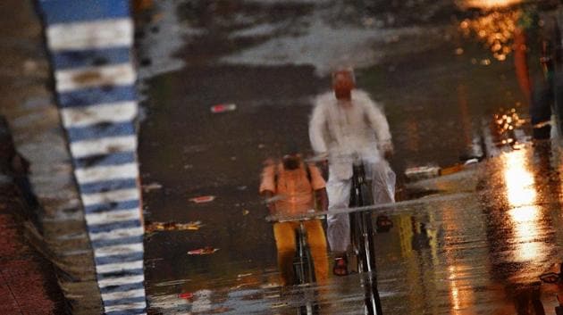 Image rotated 180 degree shows the reflection of residents riding cycles on the road covered with water puddles following unseasonal drizzle at Rajaram bridge, Karve Nagar in April.  (Pratham Gokhale/HT PHOTO) 