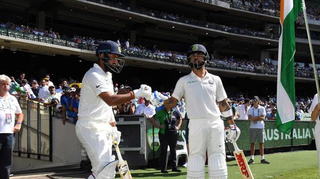 India's batsmen Virat Kohli (R) and Cheteshwar Pujara walk out to resume batting on day two of the third cricket Test match between Australia and India in Melbourne. (AFP)