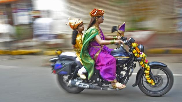 A woman rides  a motorcycle with a child riding pillion during ‘Gudi Padwa’ celebrations at Girgaon in Mumbai, Maharashtra. (Ragul Krishnan / HT Photo) 