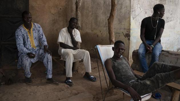 People sit outside in the shade in a village near Goudiry. From Libya, Abdrahamane called and asked his brother to sell three of their father’s cattle for money he needed to take the boat to Italy. In 2015, tragedy struck for seven Dougue families whose sons were lured by the success of another group. None have returned. After the funeral rites for Abdrahamane, only one family still holds out hope. (Felipe Dana / AP) People sit outside in the shade in a village near Goudiry. From Libya, Abdrahamane called and asked his brother to sell three of their father’s cattle for money he needed to take the boat to Italy. In 2015, tragedy struck for seven Dougue families whose sons were lured by the success of another group. None have returned. After the funeral rites for Abdrahamane, only one family still holds out hope. (Felipe Dana / AP)