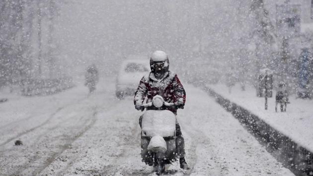 A man rides a scooter while it snows heavily in Srinagar, Jammu and Kashmir. (Waseem Andrabi / HT Photo) 