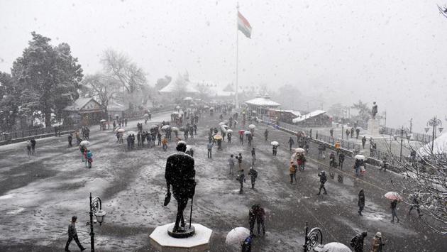 People take a stroll during the season’s first snowfall at Ridge, in Shimla, Himachal Pradesh. (Deepak Sansta / HT Photo) 