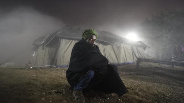 A homeless man poses for a picture during a movie screening in a temporary open-air theatre on the eve of New Year near Nigambodh Ghat, in New Delhi. Delhi’s infamous winter has made itself apparent this year, breaking a 15-year record for lowest temperatures so far. (Burhaan Kinu / HT Photo) 