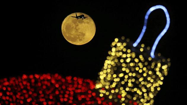 The moon shines behind decorative Christmas ornaments as an aircraft prepares for landing at the airport in the southern coastal city of Larnaca In the eastern Mediterranean island of Cyprus. (Petros Karadjias / AP) The moon shines behind decorative Christmas ornaments as an aircraft prepares for landing at the airport in the southern coastal city of Larnaca In the eastern Mediterranean island of Cyprus. (Petros Karadjias / AP)