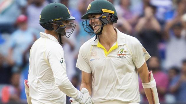 Australia's Nathan Lyon, left, shakes hands with Pat Cummins after cummins reached his 50 during play on day four of the third cricket test between India and Australia in Melbourne. (AP)
