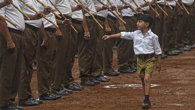 A boy walks as volunteers of Rashtriya Swayamsevak Sangh (RSS) stand before ‘Path Sanchalan’ (route march) on Vijyadashmi festival at Shukrawar Peth on October 18. (Pratham Gokhale/HT Photo) 