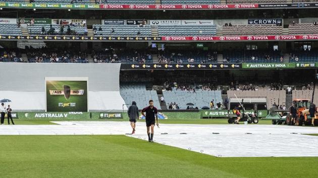 Melbourne cricket ground curating staff place pegs into the rain covers as the start of play is delayed during day five of the third cricket test between India and Australia in Melbourne. (AP) Melbourne cricket ground curating staff place pegs into the rain covers as the start of play is delayed during day five of the third cricket test between India and Australia in Melbourne. (AP)