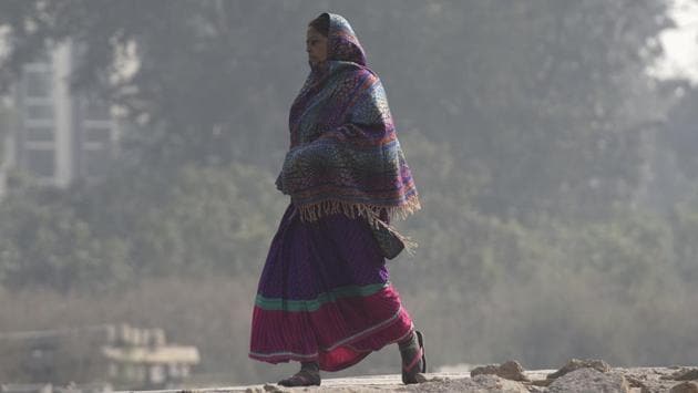 A woman wears warm clothes to protect herself from cold on a winter morning, at Okhla Railway Station, in New Delhi, India.(Burhaan Kinu/HT PHOTO)