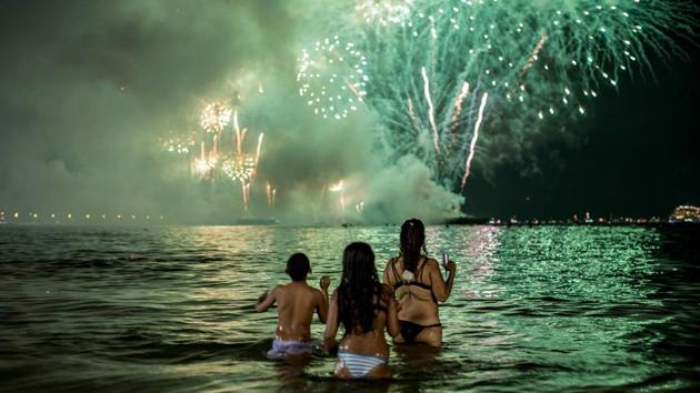 People watch fireworks from the water on Copacabana beach during the New Year celebration in Rio de Janeiro, Brazil. (Daniel Ramalho / AFP) 