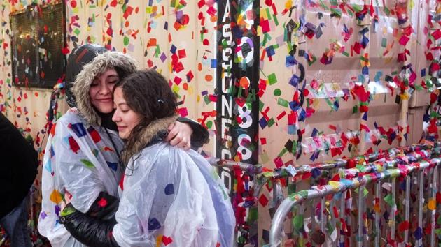 As rain-soaked confetti sticks to most surfaces, revelers embrace as they take part in a New Year's celebration in Times Square, New York. (Craig Ruttle / AP Photo) 