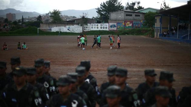 Men play soccer as soldiers line up in a neighbourhood occupied by gangs known as El Hoyo in Tegucigalpa. Danger in Honduras is never far away. For comparison, the latest statistics in the United States state there were 5.3 murders per 100,000 in 2017, according to the FBI’s most recent report on its website. (Edgard Garrido / REUTERS) Men play soccer as soldiers line up in a neighbourhood occupied by gangs known as El Hoyo in Tegucigalpa. Danger in Honduras is never far away. For comparison, the latest statistics in the United States state there were 5.3 murders per 100,000 in 2017, according to the FBI’s most recent report on its website. (Edgard Garrido / REUTERS)