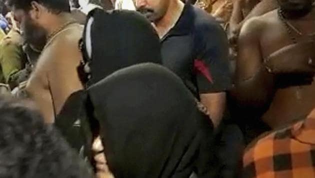 A still from a video grab shows two women, both in black outfits, walk to offer prayers at Lord Ayyappa Temple in Sabarimala, Kerala.(PTI photo)