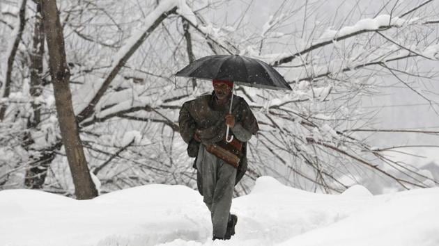 A man walks through a snow-covered road during fresh snowfall at Tangmarg road about 38 kilometers from Srinagar, Jammu and Kashmir, on Wednesday, January 2, 2019.(Waseem Andrabi / HT Phot o)