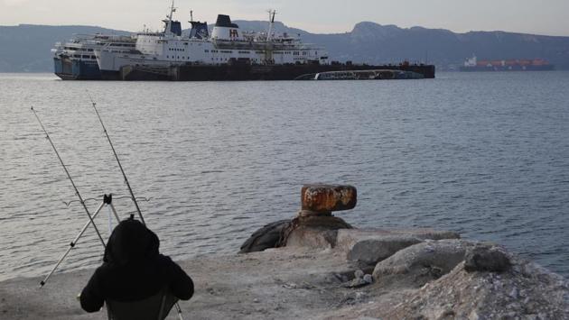 A man fishes as half sunken and abandoned ships are moored in the Gulf of Elefsina. “It is the sins of many years which we now have come (to solve),” said Gargaretas. “We are trying in a very short period of time and with huge bureaucratic and legal hurdles to remove all these ships from the area.” (Thanassis Stavrakis / AP) A man fishes as half sunken and abandoned ships are moored in the Gulf of Elefsina. “It is the sins of many years which we now have come (to solve),” said Gargaretas. “We are trying in a very short period of time and with huge bureaucratic and legal hurdles to remove all these ships from the area.” (Thanassis Stavrakis / AP)