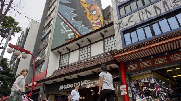 People walk under a mural of a Samurai in Sao Paulo. Like many immigrant groups, the early settlers planned to return home in two to five years and start new lives with their earnings. But they quickly realized they would never save enough for a return ticket. Many eventually migrated to urban centres or to other rural areas. (Victor R. Caivano / AP) People walk under a mural of a Samurai in Sao Paulo. Like many immigrant groups, the early settlers planned to return home in two to five years and start new lives with their earnings. But they quickly realized they would never save enough for a return ticket. Many eventually migrated to urban centres or to other rural areas. (Victor R. Caivano / AP)
