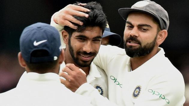 Virat Kohli congratulates fast bowler Jasprit Bumrah (L) after he took the wicket of Australia's batsman Peter Handscomb.(AFP)
