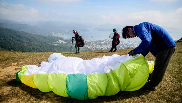 A man helps prepare the wing for Giovanni Lam (L) before he and Keith Yung (C) paraglide in tandem. With most young Hong Kongers priced out of the city’s eye-watering property market -- often living with parents in cramped flats well into their thirties -- paragliding is one of a number of outdoor sports that offer release from the stress of the concrete jungle. (Anthony Wallace / AFP) A man helps prepare the wing for Giovanni Lam (L) before he and Keith Yung (C) paraglide in tandem. With most young Hong Kongers priced out of the city’s eye-watering property market -- often living with parents in cramped flats well into their thirties -- paragliding is one of a number of outdoor sports that offer release from the stress of the concrete jungle. (Anthony Wallace / AFP)