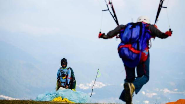 A paraglider (R) runs to take off from Ma On Shan peak. Once the clouds dispersed, revealing a rolling tapestry of parkland below, Lam ordered his tandem protege Keith Yung to walk against the wind as he pulled on lines attached to the canopy behind them. Within seconds, the glider caught the breeze and the duo took off. (Anthony Wallace / AFP) A paraglider (R) runs to take off from Ma On Shan peak. Once the clouds dispersed, revealing a rolling tapestry of parkland below, Lam ordered his tandem protege Keith Yung to walk against the wind as he pulled on lines attached to the canopy behind them. Within seconds, the glider caught the breeze and the duo took off. (Anthony Wallace / AFP)