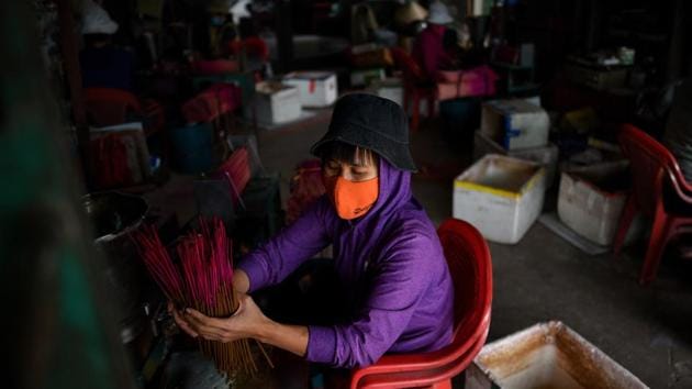 Workers prepare incense sticks at a workshop in Quang Phu Cau. After they’ve dried out, women donning cloth face masks coat the sticks with aromatic incense paste before re-drying them and shipping them off for packaging. (Manan Vatsyayana / AFP) Workers prepare incense sticks at a workshop in Quang Phu Cau. After they’ve dried out, women donning cloth face masks coat the sticks with aromatic incense paste before re-drying them and shipping them off for packaging. (Manan Vatsyayana / AFP)