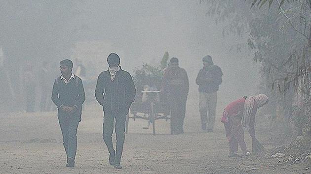 Commuters protect themselves from the cold at Akshardham on Tuesday morning.(HT Photo)