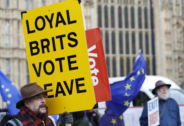 A vote leave pro-Brexit demonstrator holds a placard with anti Brexit protesters in the background as they voice their opinions outside the Palace of Westminster, in London, Wednesday, Jan. 9, 2019. The British government was bringing Prime Minister Theresa May's Brexit deal back to Parliament for possible approval next week, although many lawmakers are expected to vote against the deal. (AP Photo/Alastair Grant)(AP)