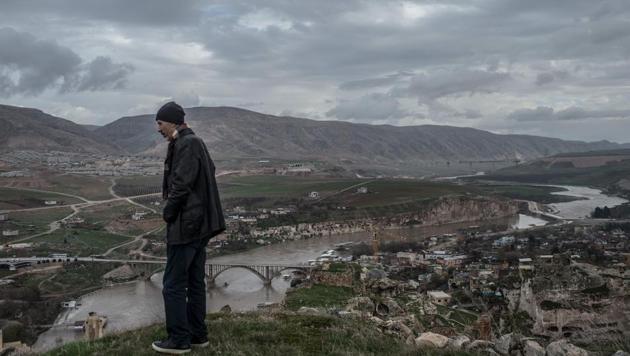 From the ancient citadel overlooking the valley, Ridvan Ayhan looks at the Tigris with a furrowed brow. The river that supported his family’s town for generations will soon destroy it. “My grandchildren will not see where I grew up, where I lived. They will ask me, ‘Grandpa, where do you come from? Where did you live?’ What will I do? Show them the lake?” asks Ayhan, readjusting the scarf over his face. (Bulent Kilic / AFP) From the ancient citadel overlooking the valley, Ridvan Ayhan looks at the Tigris with a furrowed brow. The river that supported his family’s town for generations will soon destroy it. “My grandchildren will not see where I grew up, where I lived. They will ask me, ‘Grandpa, where do you come from? Where did you live?’ What will I do? Show them the lake?” asks Ayhan, readjusting the scarf over his face. (Bulent Kilic / AFP)