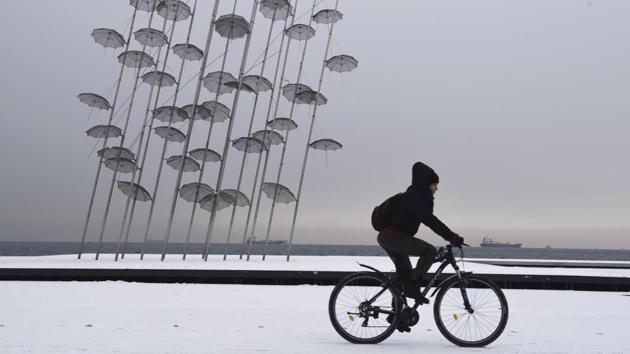 A woman cycles in front of the ‘Umbrellas’ sculpture by the seafront of Thessaloniki. A Swiss researcher, Antoine Viredaz visiting from Lausanne, was delighted by the unexpected snowfall. “I was not really expecting that much snow, but it’s great,” he said. (Giannis Papanikos / AP) A woman cycles in front of the ‘Umbrellas’ sculpture by the seafront of Thessaloniki. A Swiss researcher, Antoine Viredaz visiting from Lausanne, was delighted by the unexpected snowfall. “I was not really expecting that much snow, but it’s great,” he said. (Giannis Papanikos / AP)